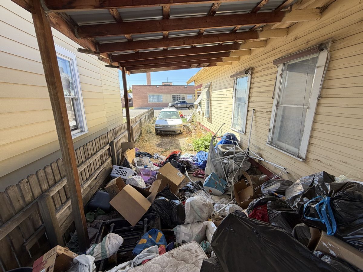 Carport side yard full of household junk before removal